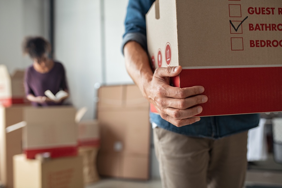 Man carrying moving box through house