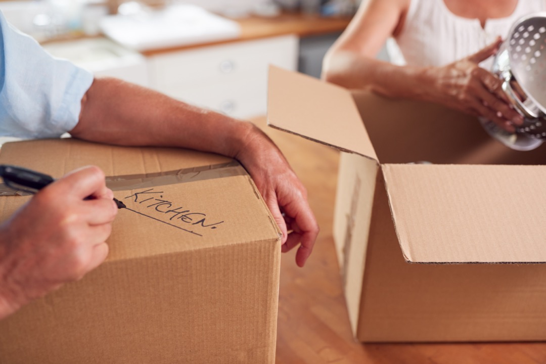 Couple packing up kitchen items into boxes