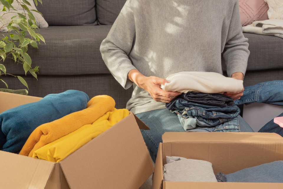 Woman packing clothing into boxes for storage